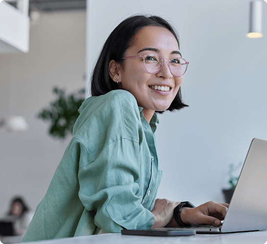 A woman smiles in front of a laptop