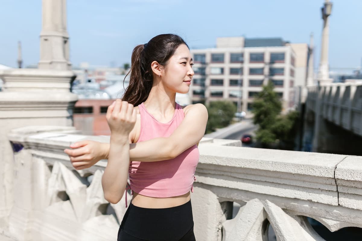 An athletic woman stretches her arms outside